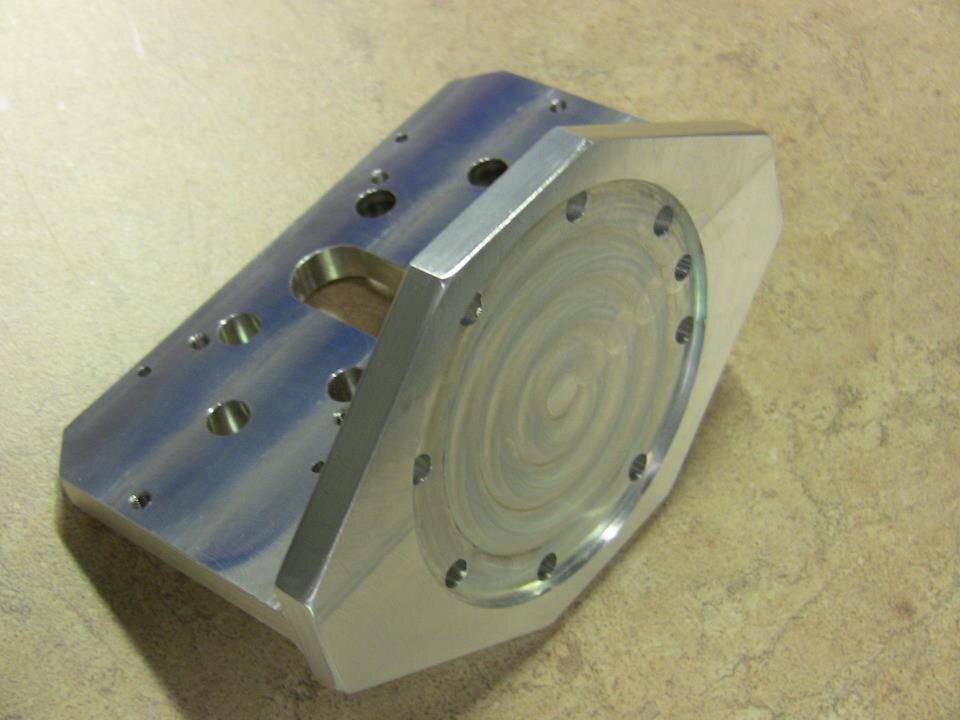 Machined aluminum mounting plate with a recessed circular face and drilled holes