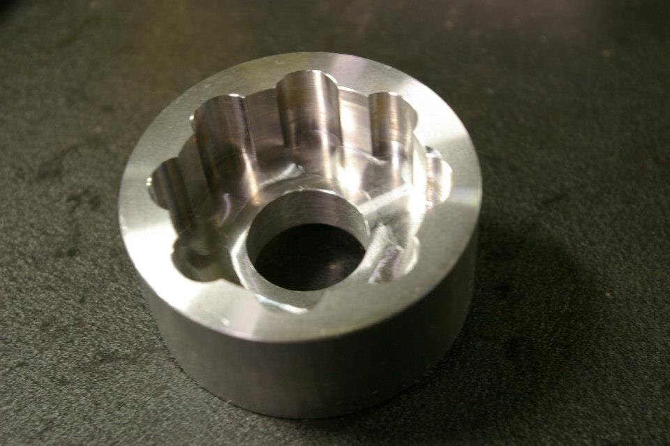 Round steel part with a milled scalloped pocket and through bore